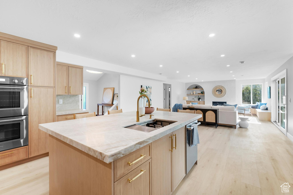 Kitchen with light brown cabinets, a sink, appliances with stainless steel finishes, recessed lighting, and light wood-style floors