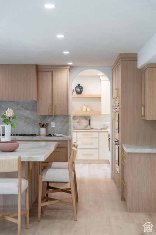 Kitchen with light countertops, open shelves, decorative backsplash, white gas cooktop, and recessed lighting