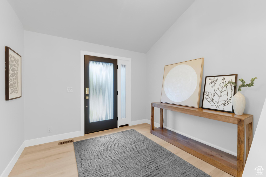 Foyer entrance featuring wood finished floors, lofted ceiling, and baseboards