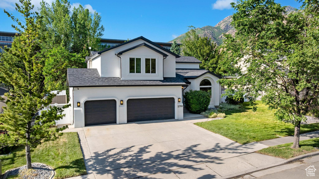 View of front of home featuring stucco siding, a garage, driveway, a shingled roof, and a front lawn