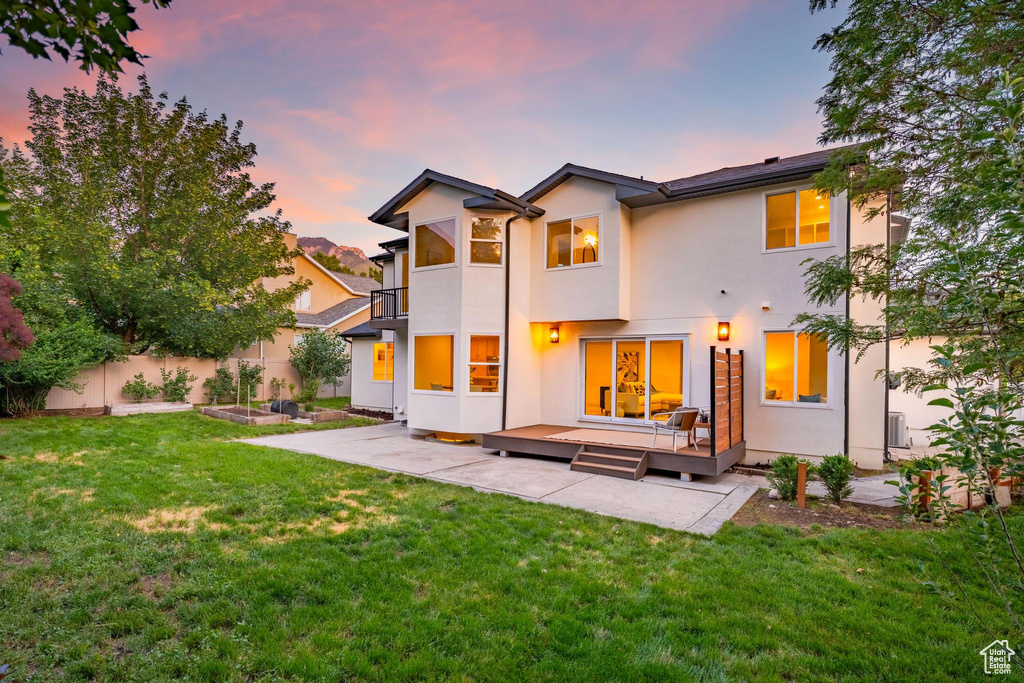 Back of house with stucco siding, a patio area, a wooden deck, and a garden