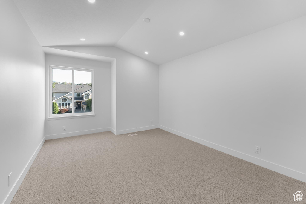 Unfurnished room featuring recessed lighting, light colored carpet, baseboards, and vaulted ceiling
