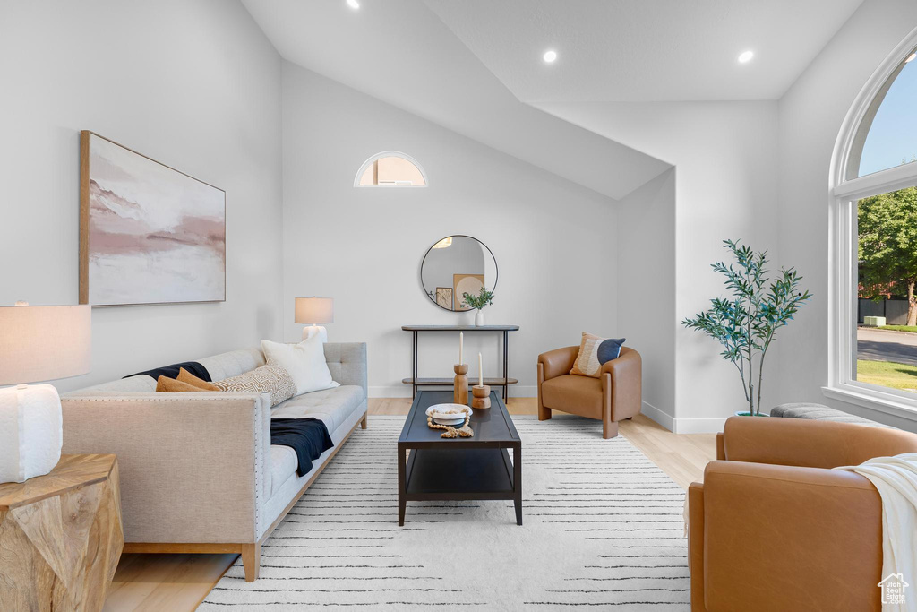 Living room with light wood-style floors, recessed lighting, baseboards, and high vaulted ceiling