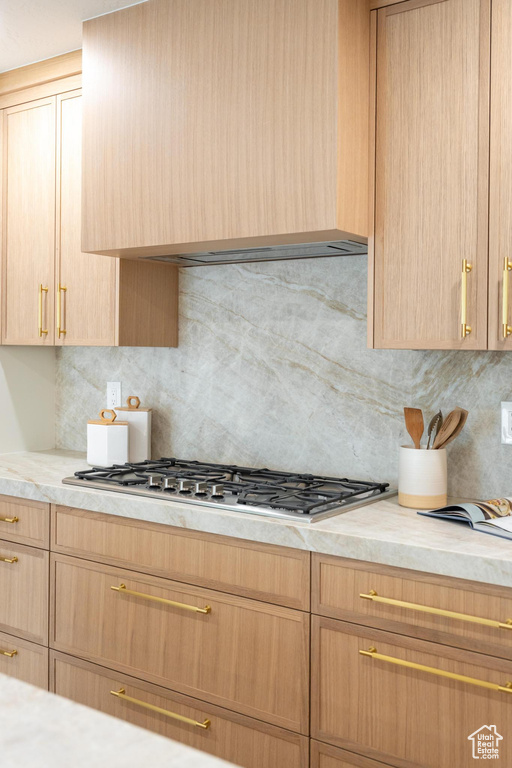 Kitchen with light brown cabinetry, light countertops, and backsplash