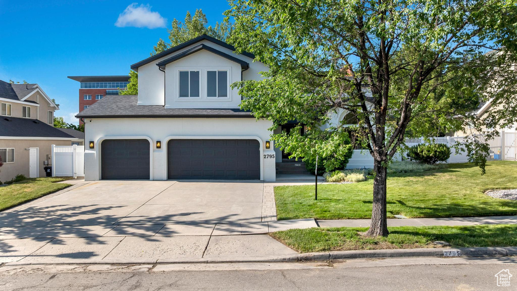 Traditional-style house with an attached garage, driveway, and stucco siding