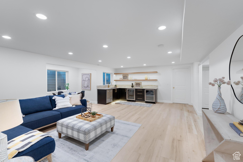 Living room featuring beverage cooler, light wood-type flooring, recessed lighting, bar, and baseboards