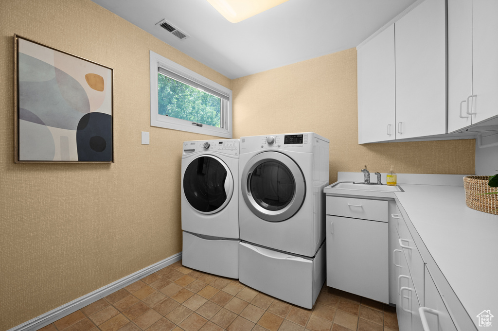 Washroom featuring washer and dryer, cabinet space, and baseboards