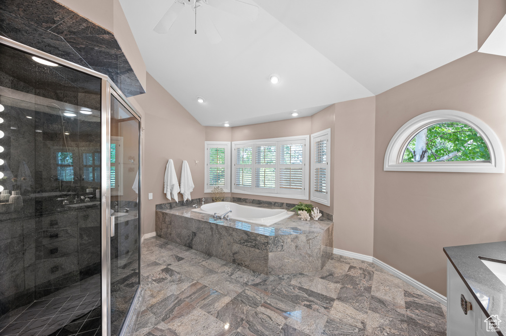 Full bathroom featuring vaulted ceiling, a garden tub, a shower stall, vanity, and baseboards
