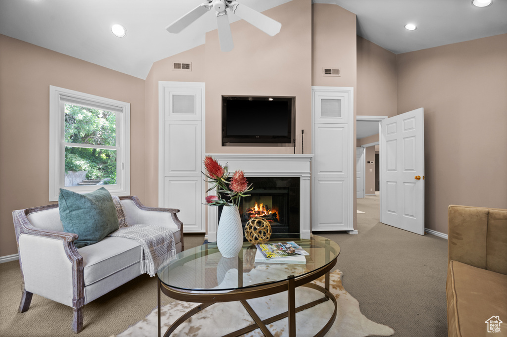 Carpeted living room featuring lofted ceiling, baseboards, ceiling fan, a warm lit fireplace, and recessed lighting
