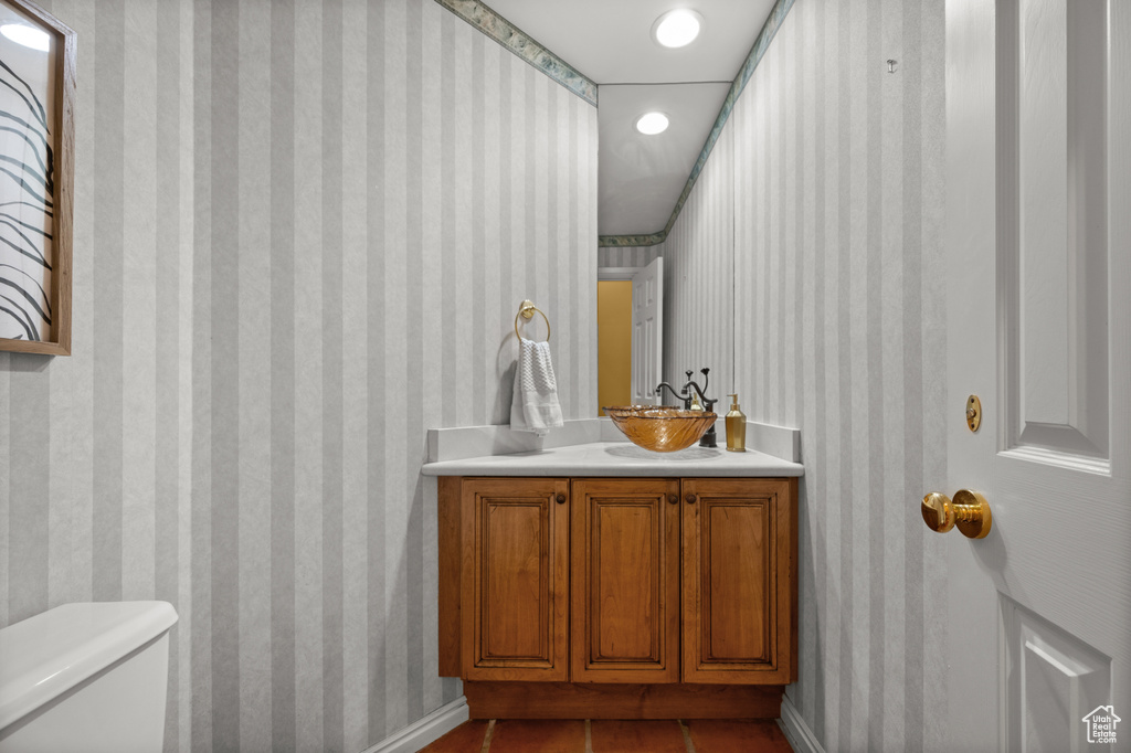 Half bath featuring toilet, vanity, wallpapered walls, tile patterned flooring, and recessed lighting
