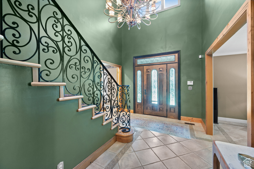 Entrance foyer with a chandelier, plenty of natural light, stairs, a towering ceiling, and baseboards