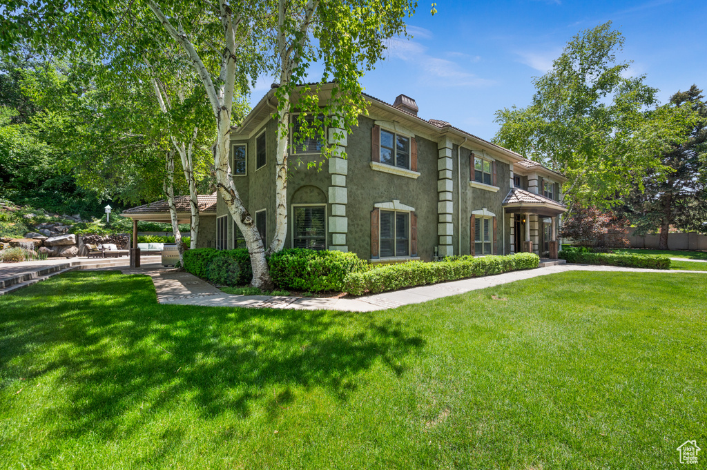 View of front facade featuring a chimney, a front lawn, and stucco siding