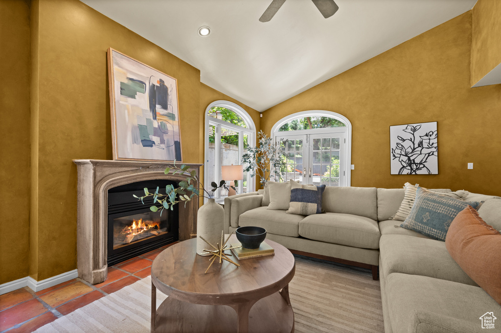 Living room featuring vaulted ceiling, a glass covered fireplace, and a ceiling fan