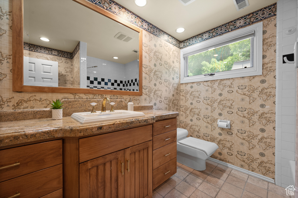 Full bathroom with vanity, toilet, a shower, wallpapered walls, and baseboards