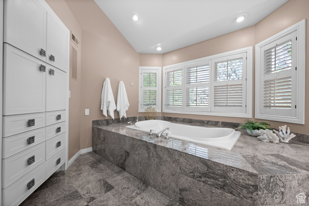 Bathroom with lofted ceiling, a bath, recessed lighting, and baseboards