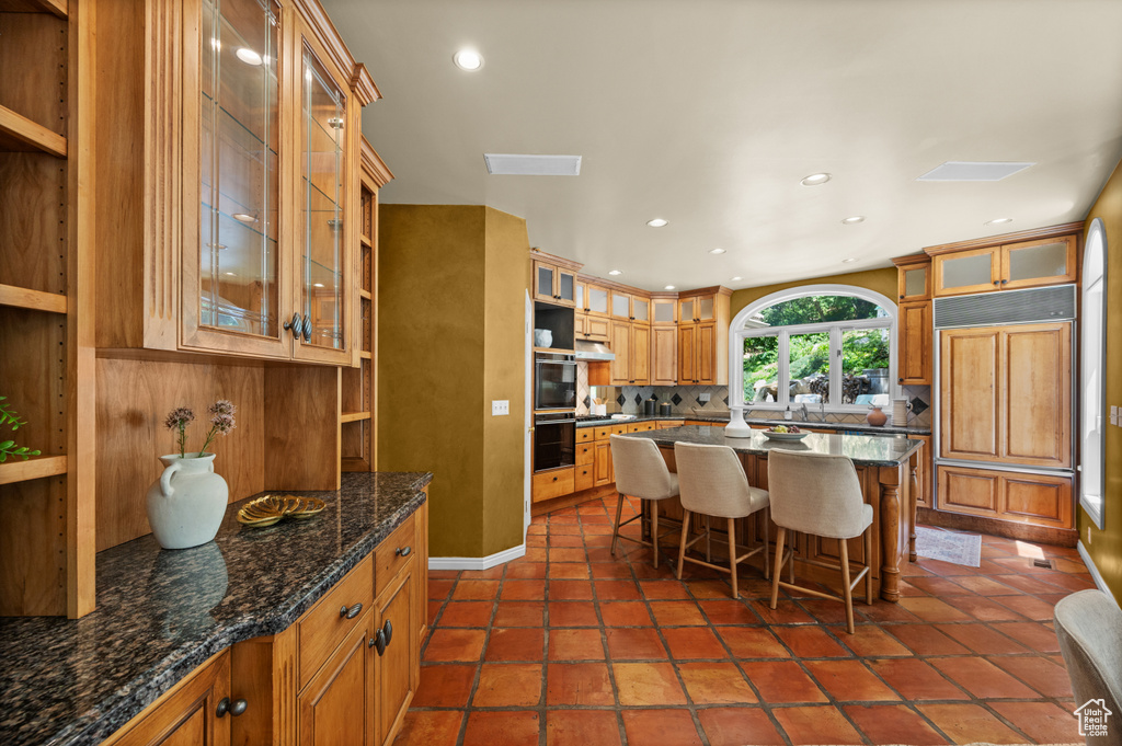 Kitchen featuring a kitchen breakfast bar, backsplash, recessed lighting, a kitchen island, and double oven