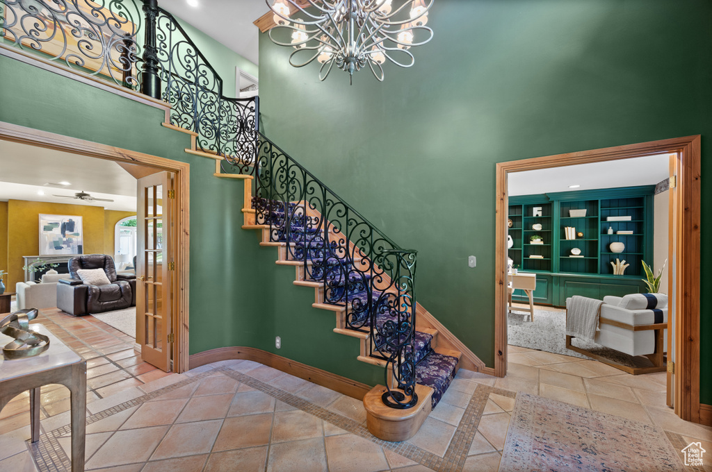 Stairs featuring a high ceiling, a chandelier, baseboards, a ceiling fan, and recessed lighting