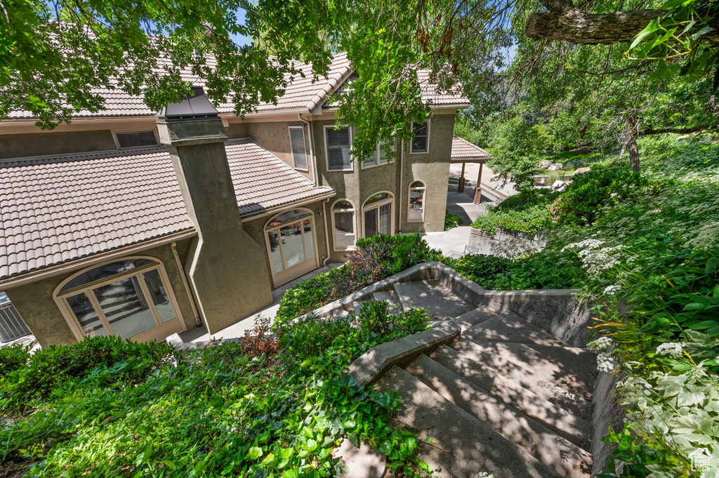 View of front of property featuring a tiled roof, stucco siding, and a patio area