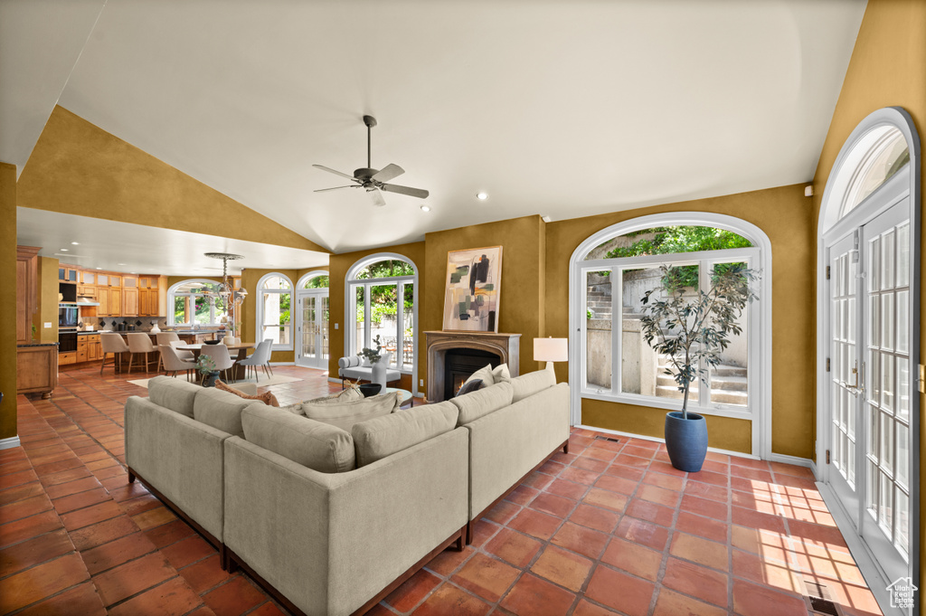 Living area with plenty of natural light, a ceiling fan, high vaulted ceiling, recessed lighting, and a warm lit fireplace