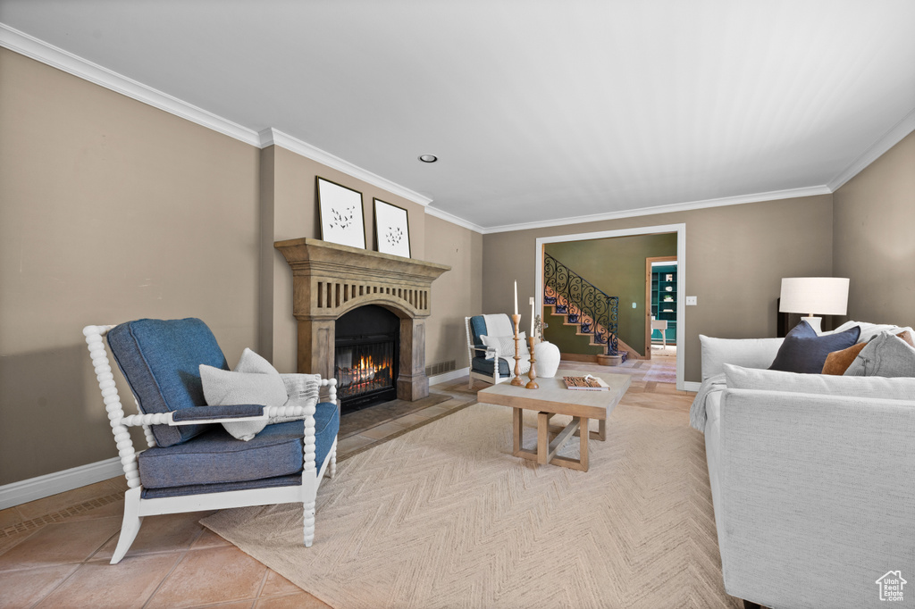 Living area featuring crown molding, stairway, baseboards, and a glass covered fireplace