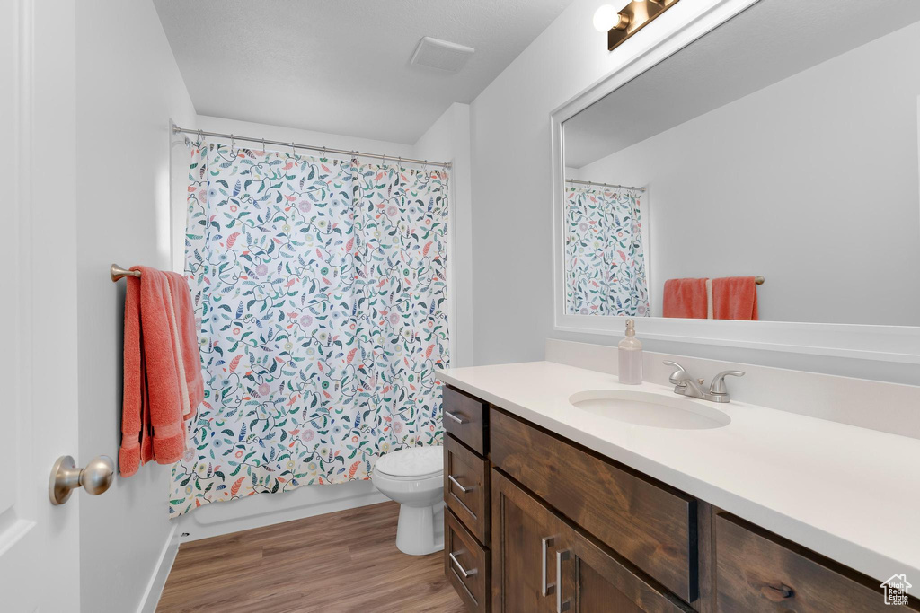 Full bath with vanity, toilet, and wood finished floors
