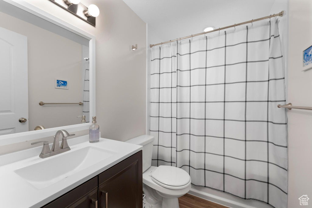 Bathroom featuring toilet, vanity, a shower with shower curtain, and wood finished floors