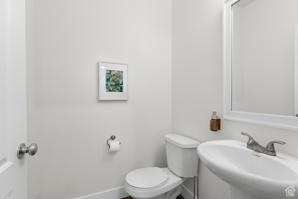Half bath with a sink, toilet, and baseboards