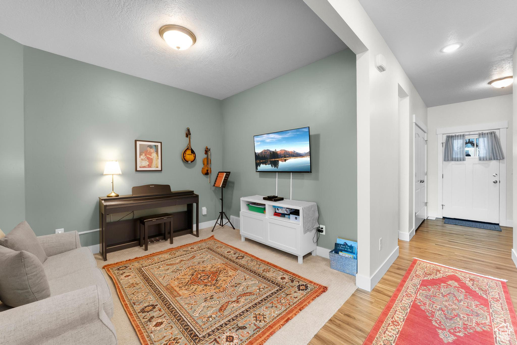 Living room with light wood-type flooring, baseboards, and a textured ceiling