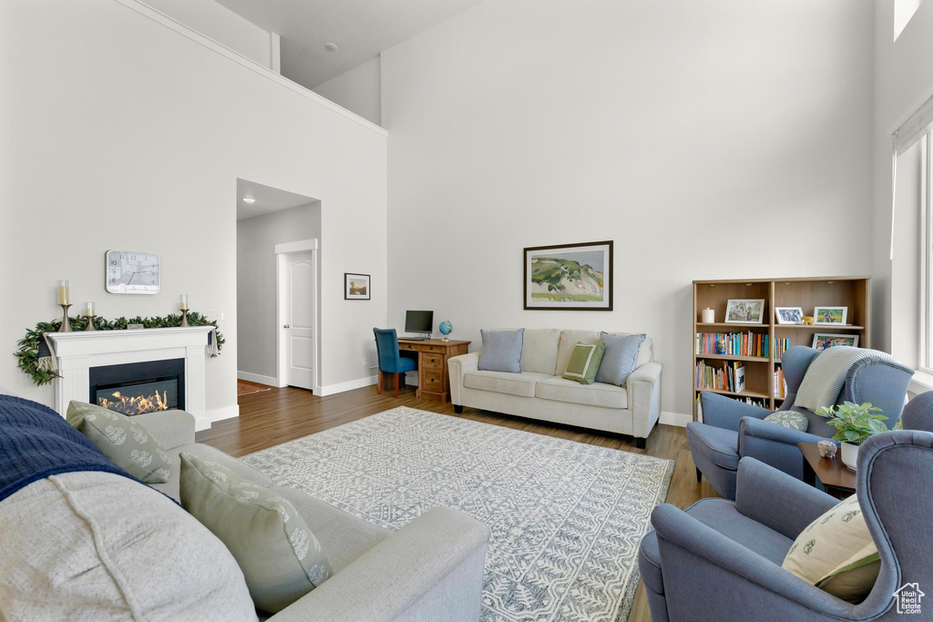 Living room featuring a high ceiling, wood finished floors, baseboards, and a glass covered fireplace