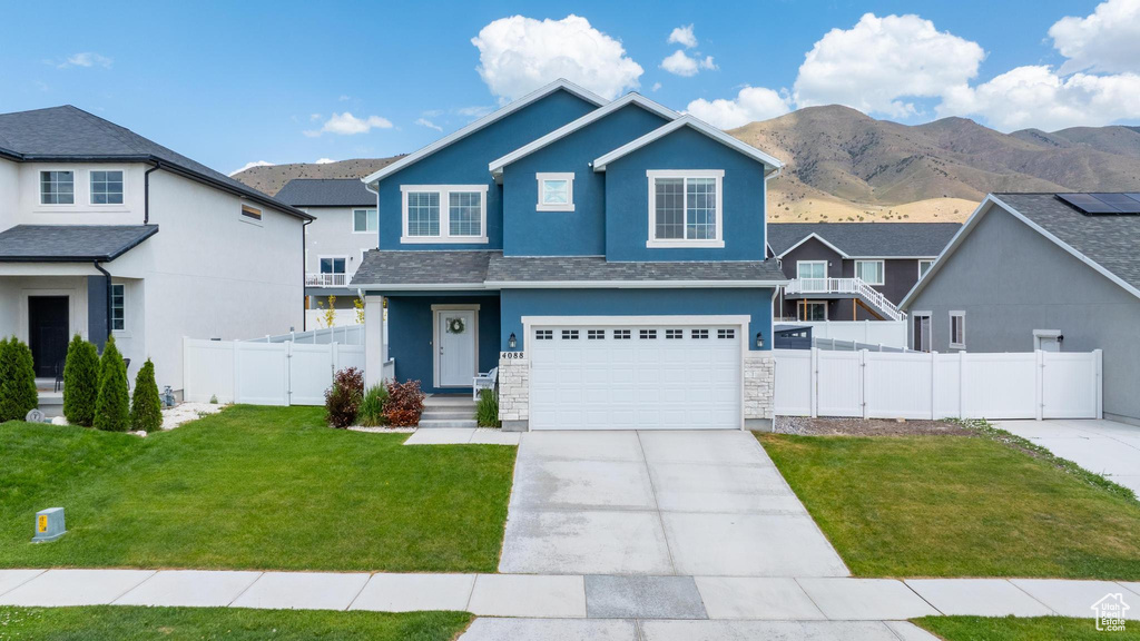 View of front of property with stucco siding, concrete driveway, a mountain view, a garage, and a gate