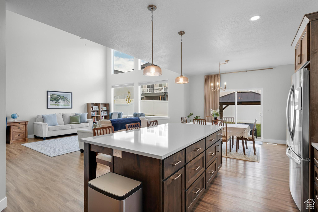 Kitchen featuring freestanding refrigerator, light wood-style flooring, a chandelier, dark brown cabinetry, and light countertops