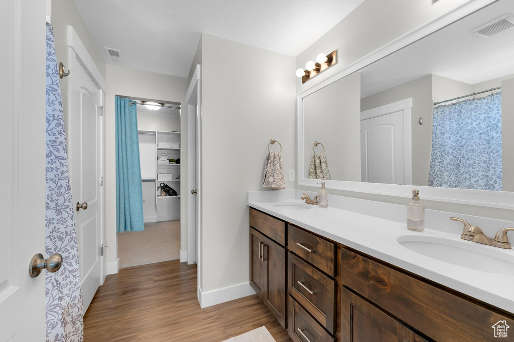 Bathroom with double vanity, wood finished floors, and baseboards