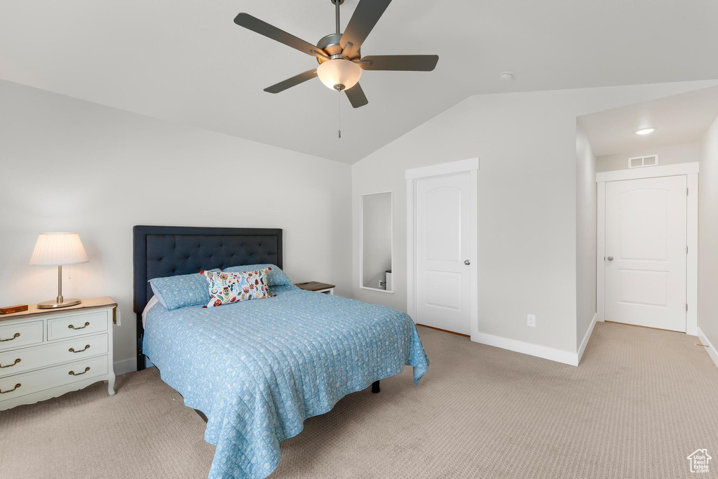 Bedroom featuring light colored carpet, baseboards, vaulted ceiling, and ceiling fan