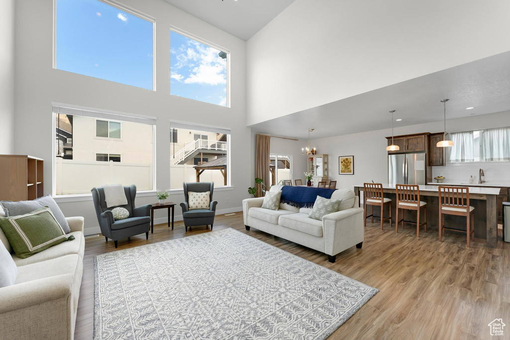Living room featuring a towering ceiling, light wood-style floors, and a chandelier
