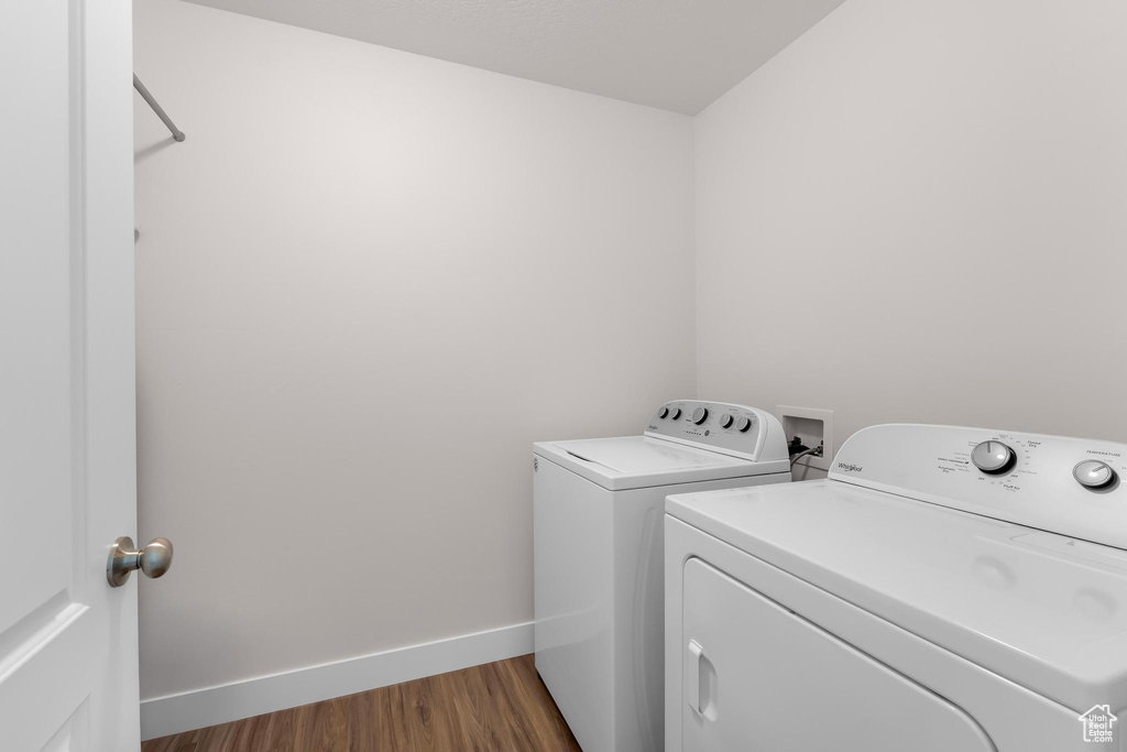 Washroom with washer and clothes dryer, dark wood finished floors, and baseboards