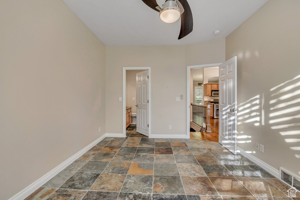 Unfurnished bedroom with stone tile flooring and baseboards