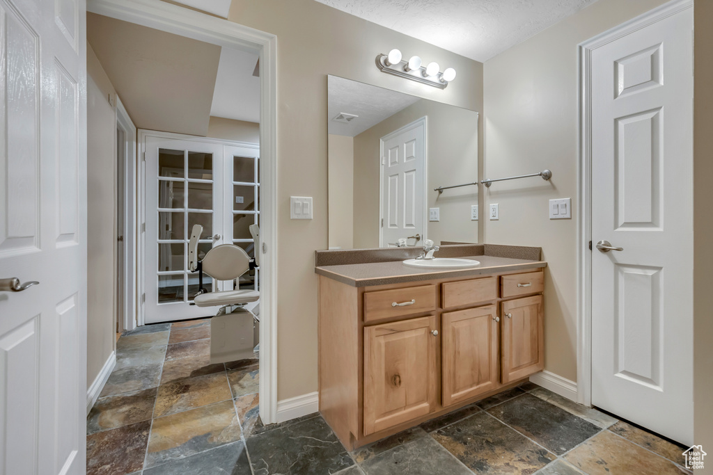 Bathroom featuring stone tile floors, baseboards, and vanity