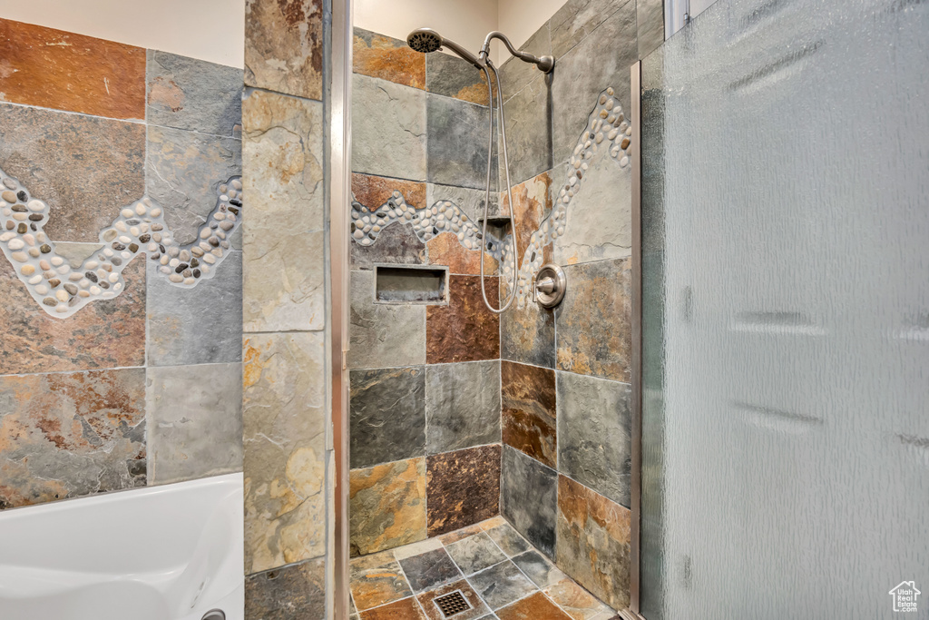 Bathroom with tiled shower and stone finish flooring