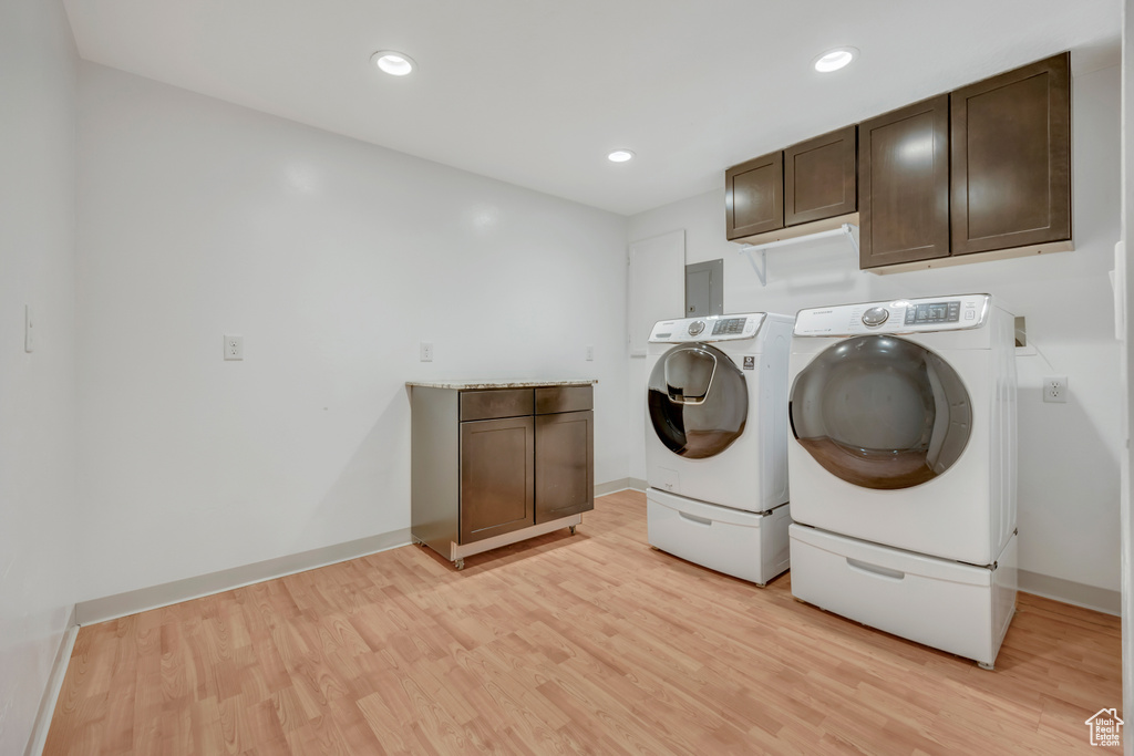 Laundry area featuring independent washer and dryer, light wood-style flooring, cabinet space, baseboards, and recessed lighting
