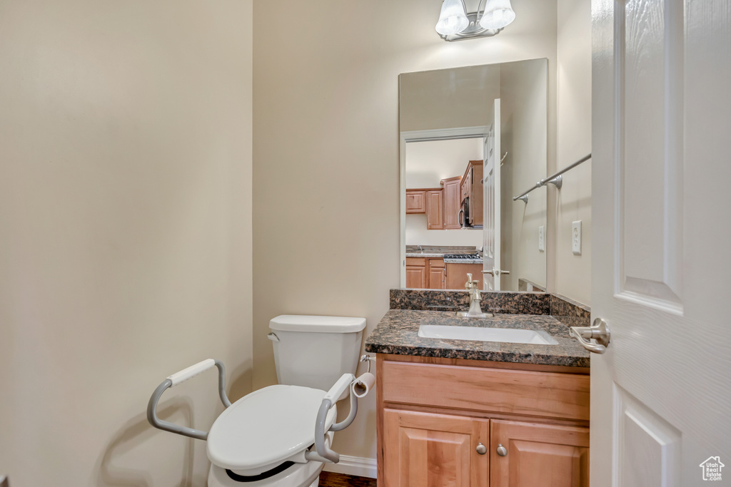 Half bath featuring vanity, toilet, and baseboards