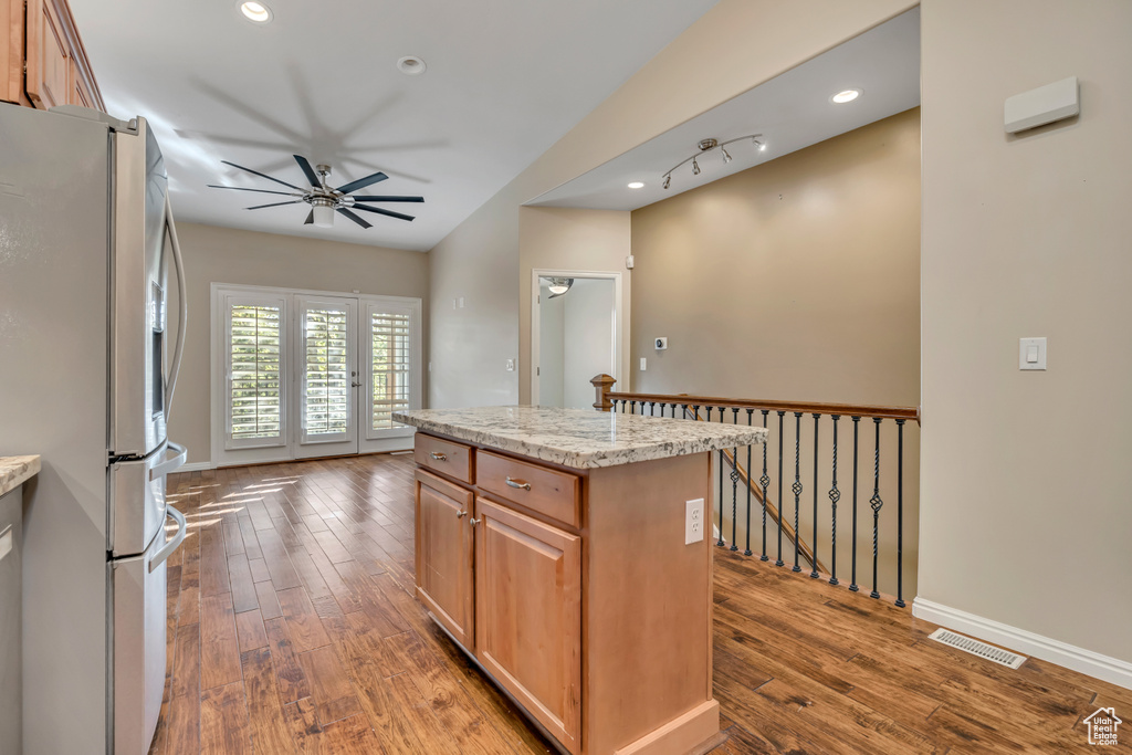 Kitchen with stainless steel refrigerator with ice dispenser, ceiling fan, hardwood / wood-style floors, a kitchen island, and vaulted ceiling