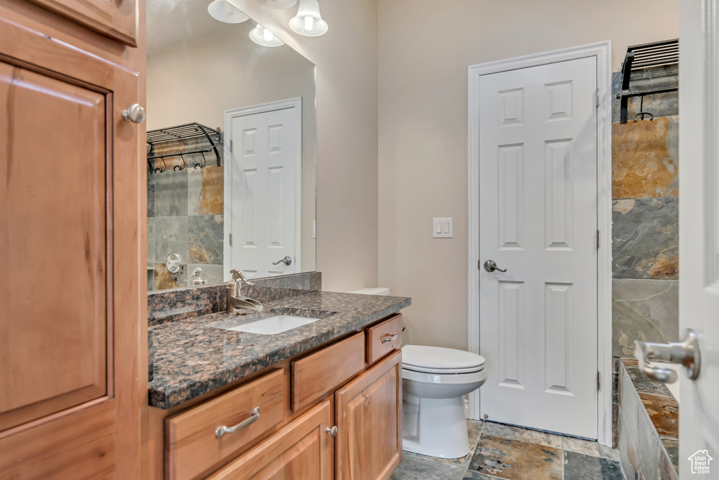 Bathroom featuring vanity, toilet, and stone finish floors
