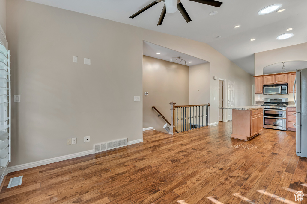 Kitchen with stainless steel appliances, a center island, light wood-style floors, lofted ceiling, and recessed lighting