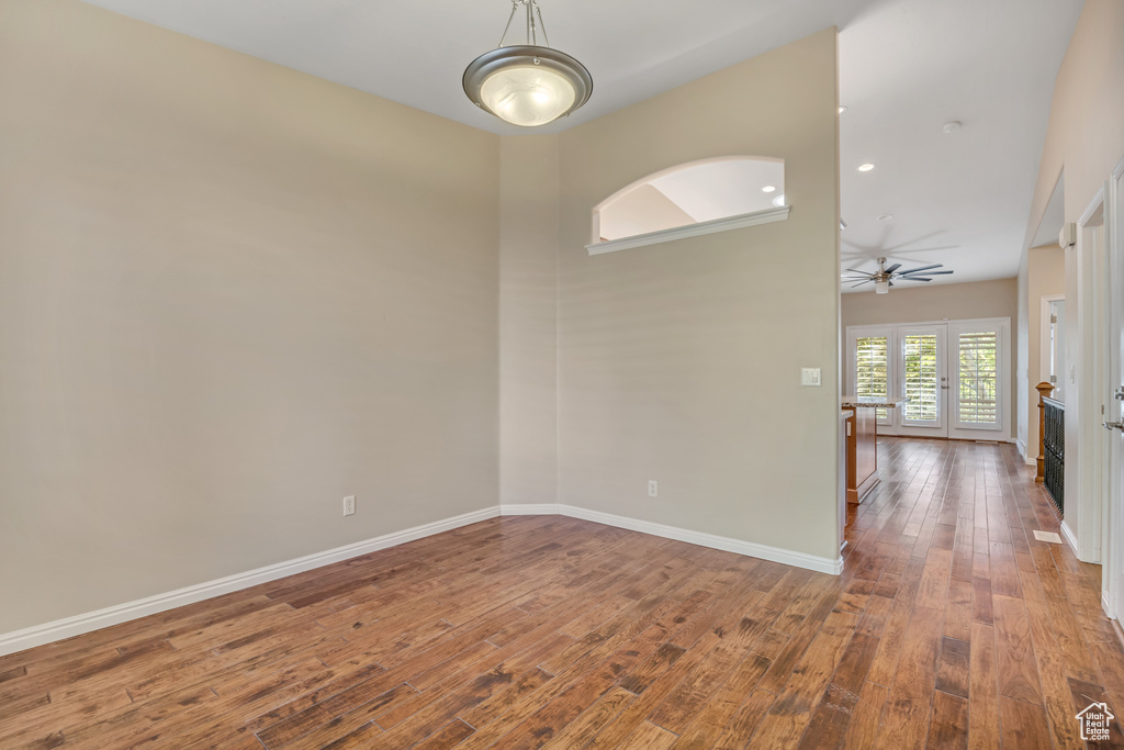 Spare room with ceiling fan, hardwood / wood-style flooring, baseboards, and a towering ceiling