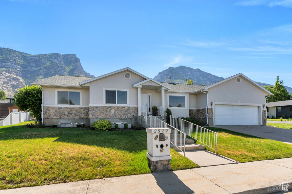 Ranch-style house with stone siding, stucco siding, a mountain view, and an attached garage