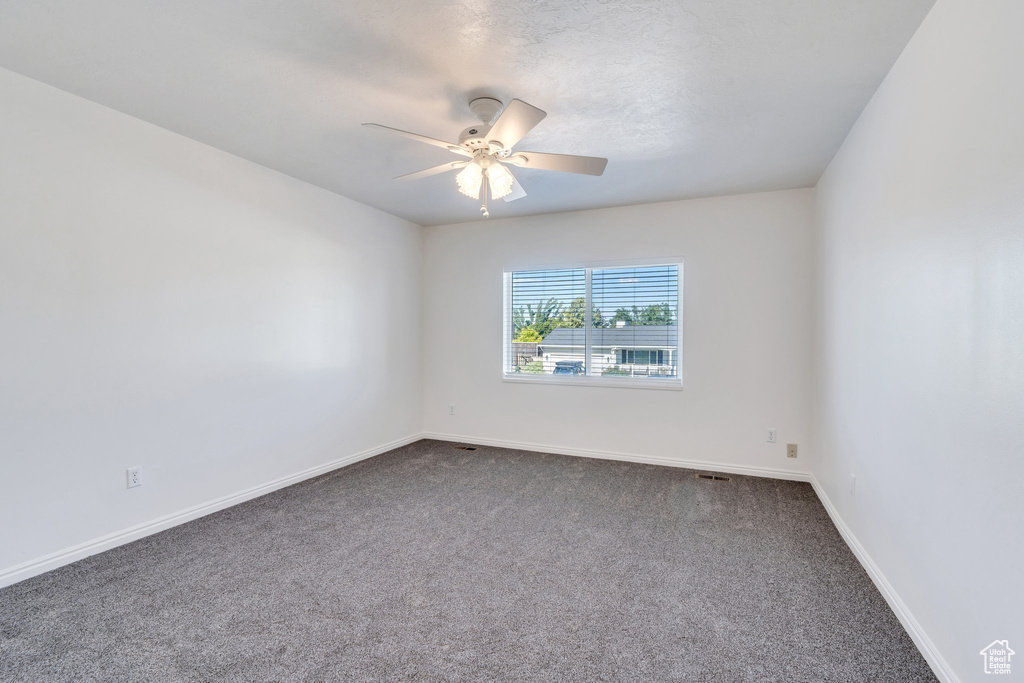 Unfurnished room featuring ceiling fan and dark colored carpet