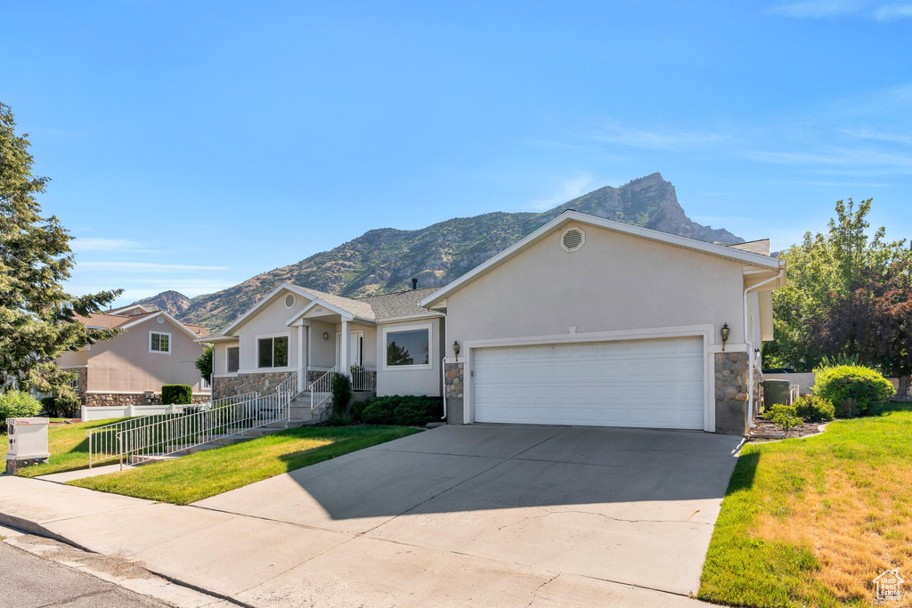Single story home with stone siding, stucco siding, a mountain view, and concrete driveway