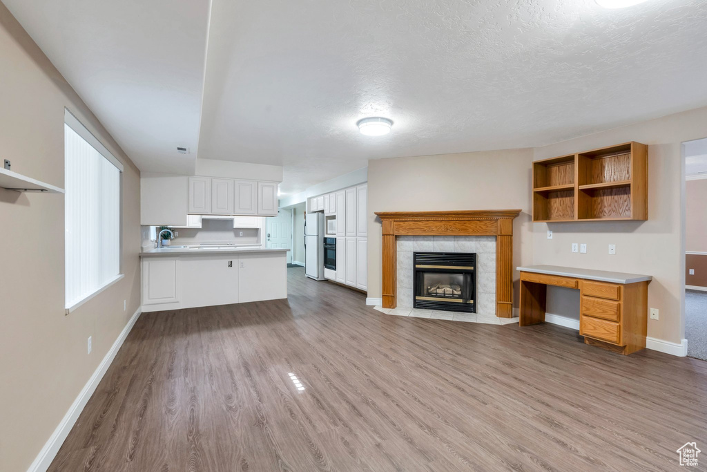 Unfurnished living room featuring wood finished floors, a fireplace, and a textured ceiling