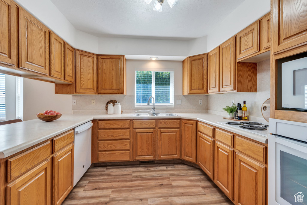 Kitchen with white appliances, light wood-style floors, light countertops, and tasteful backsplash