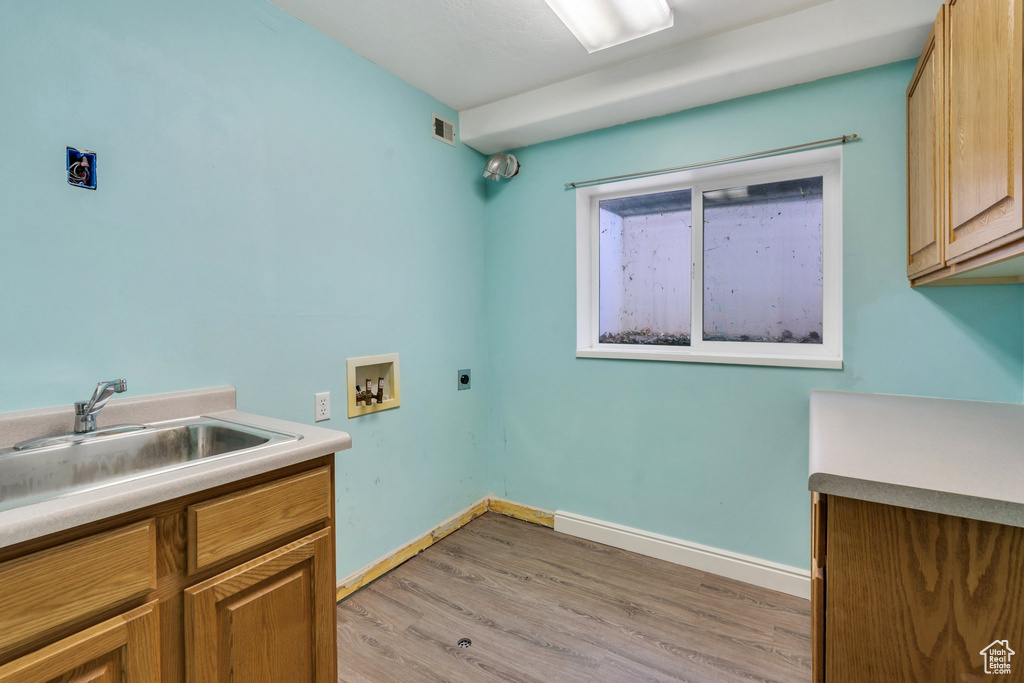 Laundry room featuring electric dryer hookup, hookup for a washing machine, cabinet space, and light wood-style flooring
